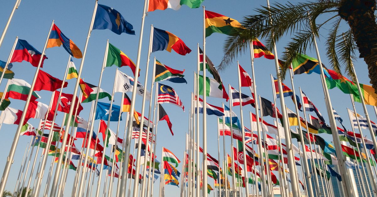 Vibrant display of international flags near Doha's skyline, symbolizing global unity.